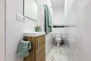 Ein modernes Badezimmer mit Waschtisch aus Holz, einem Spiegel, einem gr ünen Handtuch und einer Duschkabine aus Glas.