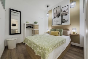 Ein Schlafzimmer mit Bett, Nachttischen, einem Kleiderschrank, einem Spiegel und Wandbildern.