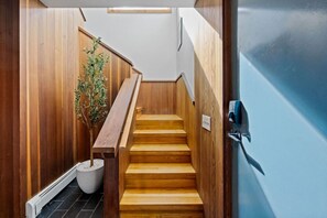 Staircase leads to an upper level with a potted plant and wooden handrails.