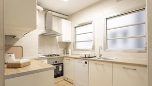 Eine moderne Küche mit Geschirrspüler, Backofen und einem Fenster mit Milchglas.