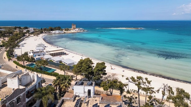 Ein Hotel an der Küste mit Blick auf den Strand, einem Swimmingpool und einem Turm im Hintergrund.