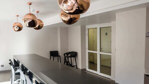 A modern kitchen with a long island, black bar stools, and copper pendant lights. - Modern Studio in Nunoa | Stylish Urban Retreat (Ñuñoa)