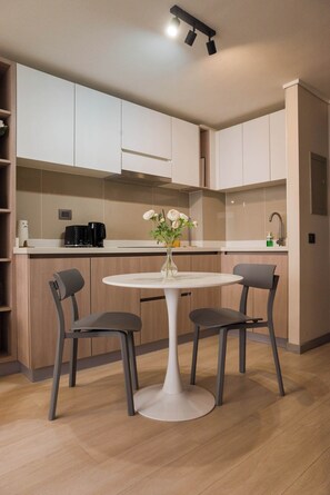 Una cocina moderna con dos sillas grises, una mesa blanca y un florero con flores.