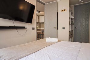 Hotellihuone, jossa on sänky, seinälle asennettu taulutelevisio, puinen vaatekaappi ja kylpyhuoneen ovi.