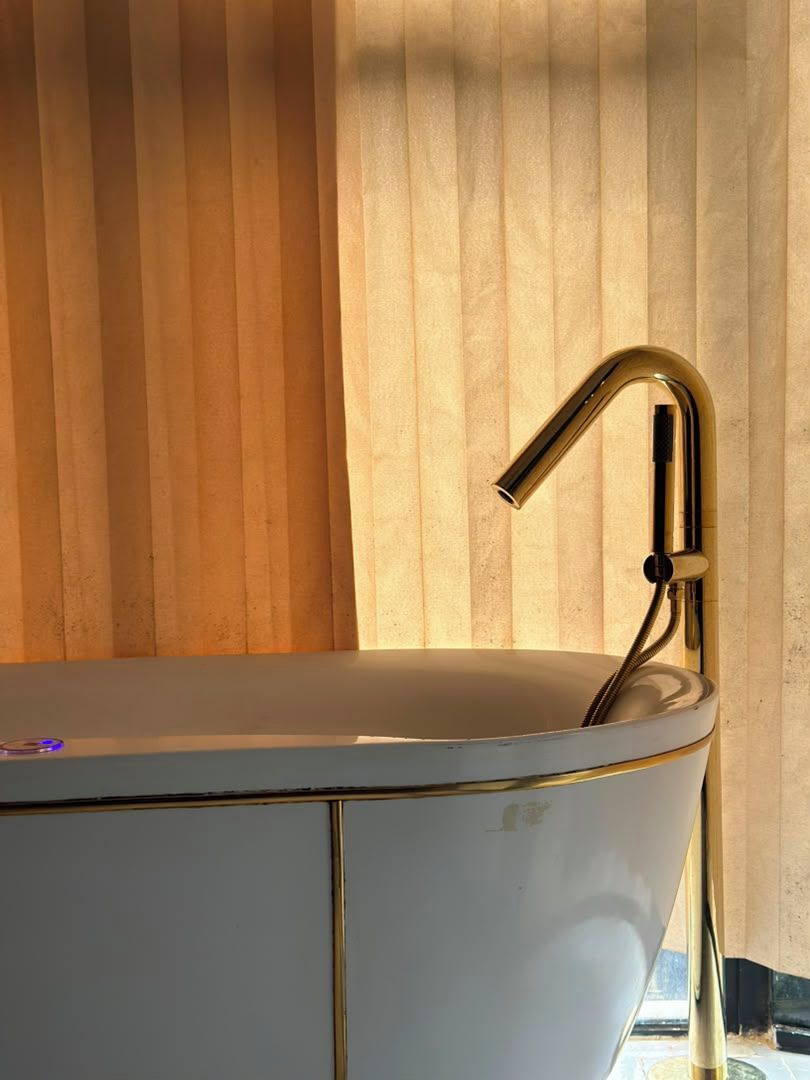 A bathtub with a gold faucet and a white interior, positioned against a wooden panel wall.