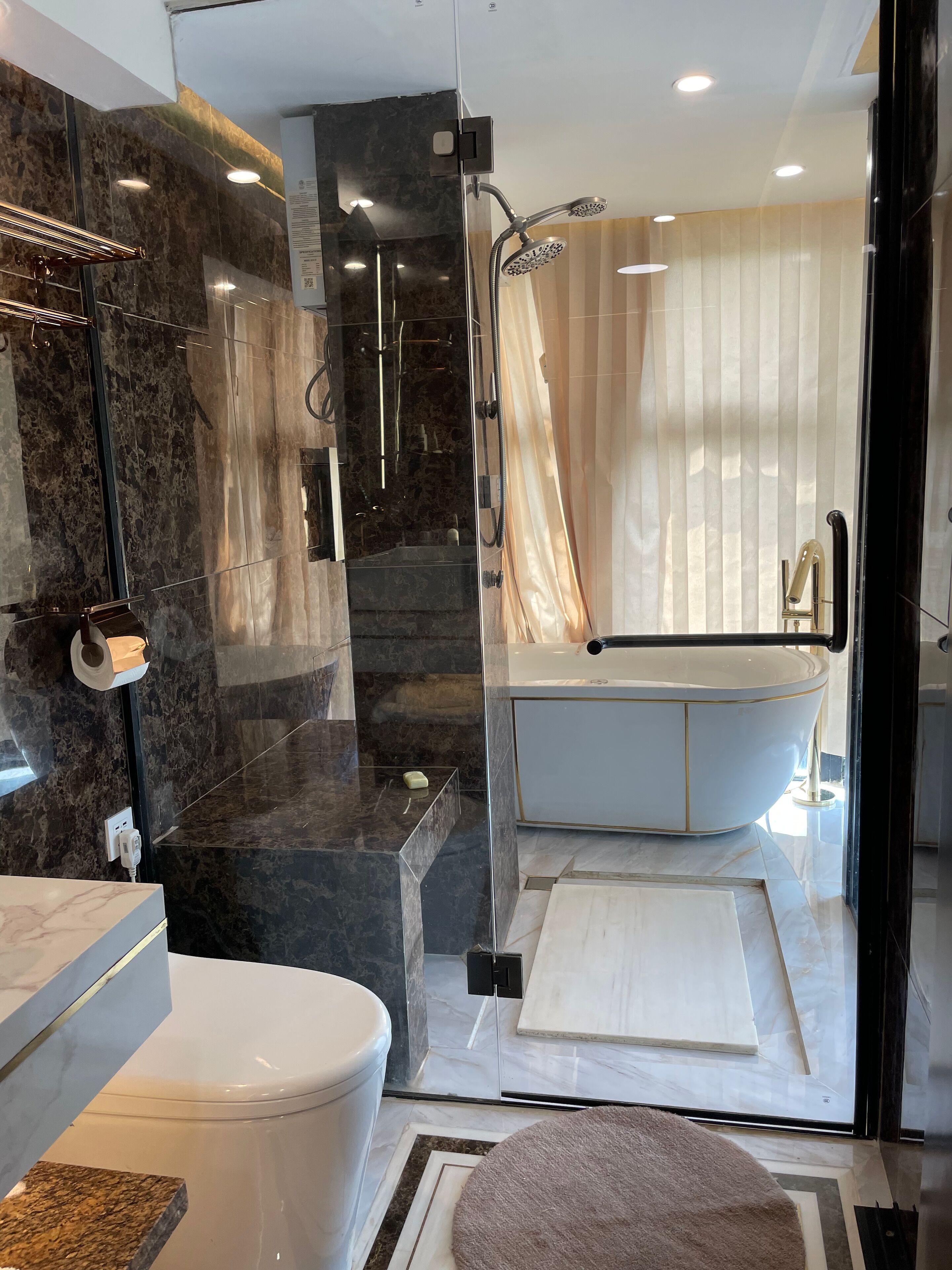 A modern bathroom with a glass-enclosed shower, a white bathtub, and a marble-tiled vanity.