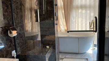 A modern bathroom with a glass-enclosed shower, a white bathtub, and a marble-tiled vanity.