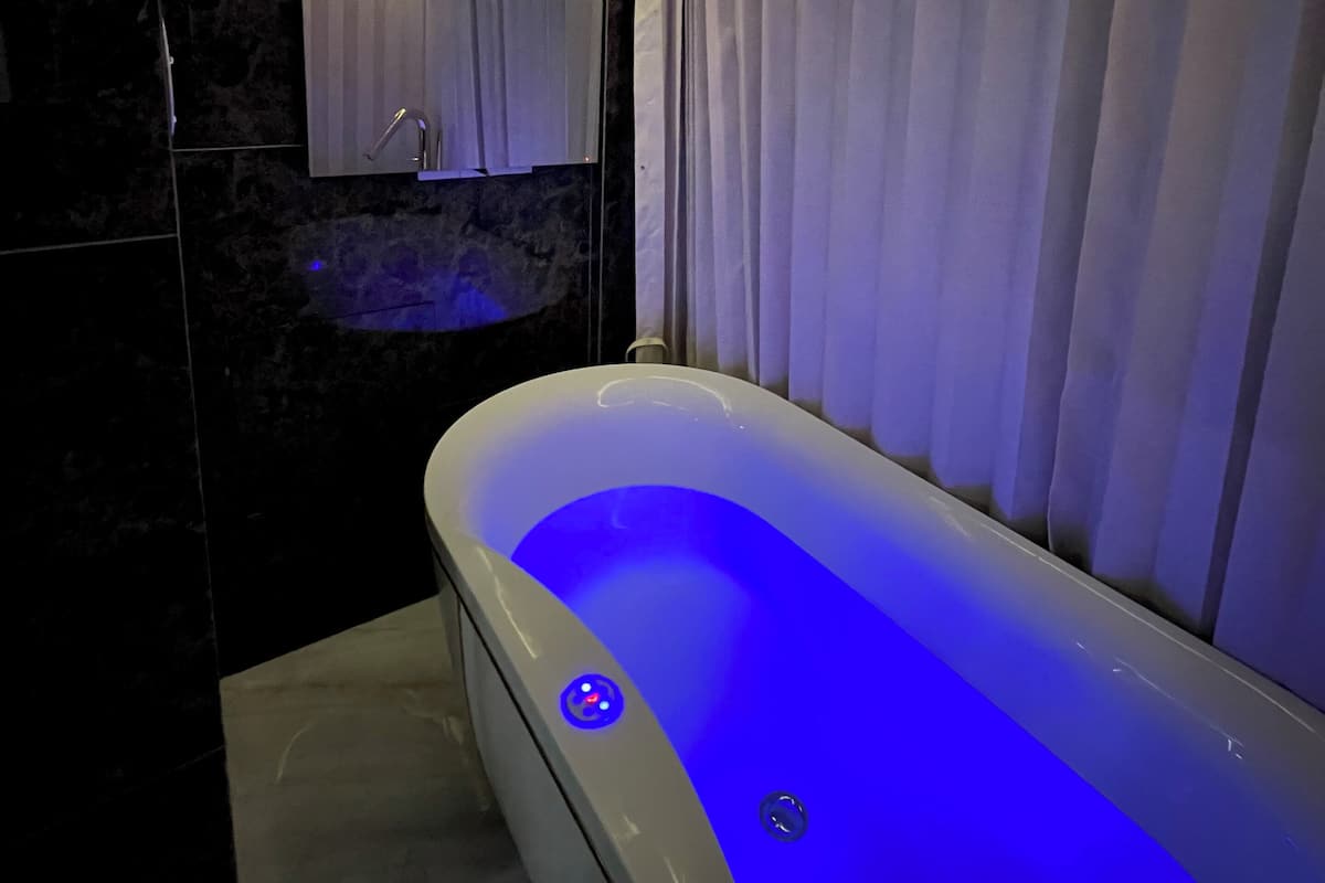 A modern bathroom with a freestanding bathtub, a wall-mounted sink, and a shower area.