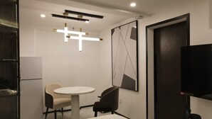 A modern hotel room with a round dining table, two chairs, a television, and a large abstract painting on the wall. - Vita Resort Golf Bastos (Yaoundé)
