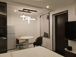 Un hotel moderno con una mesa redonda de comedor, dos sillas, un televisor y un cuadro abstracto grande en la pared.