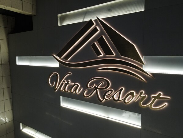 A sign for Vita Resort with a stylized mountain and wave design, and the resort name in illuminated letters.