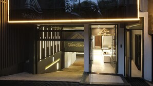 A modern hotel entrance with a glass facade, a neon sign, and a visible reception area. - Vita Resort Golf Bastos (Yaoundé)