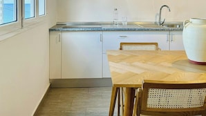 A compact kitchen with a window, a sink, and a large white vase on the counter.