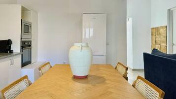 Una cocina moderna con electrodomésticos integrados, una mesa de comedor con sillas y un gran jarrón como centro de mesa.