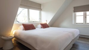 A bedroom with a large bed, two pillows, a bedside table, and a window. - Harry, Luxury property in center of NES (NES AMELAND)