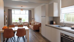 A modern kitchen with a dining area, featuring a dining table, chairs, a sofa, and a built-in oven. - Harry, Luxury property in center of NES (NES AMELAND)