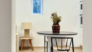 A modern kitchen with a round dining table, a chair, a potted plant, and a window with a view of trees. - Canaryislandshost I Cactus II (Mala)