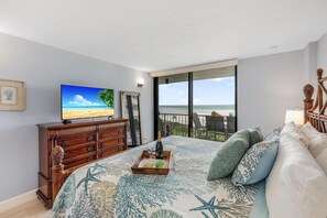A bedroom with a bed, a dresser, a TV, and a balcony with a view of the ocean. - Sw-facing Beachfront Condo With Pool/gym/pickleball (Marco Island)