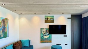 Una sala de estar moderna con un sofá azul, una mesa de centro redonda y un televisor de pantalla plana montado en la pared.