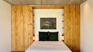 Un dormitorio con cama, paneles de madera, un cuadro y una mesita de noche.
