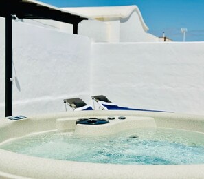 Un jacuzzi con dos sillas reclinables, rodeado de paredes blancas.