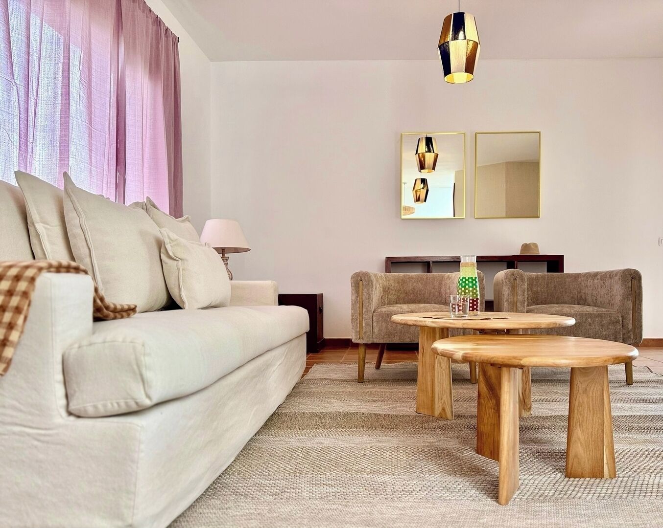 Een moderne woonkamer met een bank, twee fauteuils, een salontafel, een lamp en een televisie.