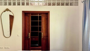 Un dormitorio con un armario de madera, un espejo y una ventana con vidrio esmerilado.