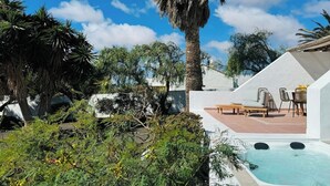 A pool area with lounge chairs and a hot tub, surrounded by lush greenery and palm trees. - Canaryislandshost l Las Palmeras (Nazaret)