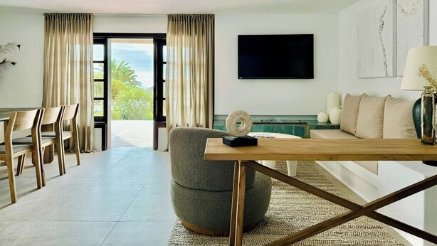 A modern living room with a sofa, a coffee table, and a TV mounted on the wall. - Canaryislandshost l Las Palmeras (Nazaret)