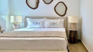 Une chambre à coucher bien rangée, avec un lit, deux tables de chevet dotées de lampes et trois miroirs fixés au mur.