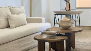 Un salon moderne avec un canapé, une table basse ronde en bois, une lampe et un vase posé sur une table.