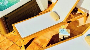 Ein Zimmer mit Whirlpool, zwei Holzliegestühlen, einem Handtuch und einer Lotionflasche.