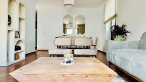 Ein modernes Wohnzimmer mit einem Holztisch, einem grauen Sofa und einem Essbereich mit Stühlen und einem Tisch.
