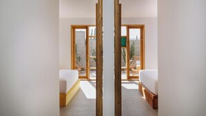 A modern bedroom with two beds, a large sliding glass door leading to a balcony with a view of a desert landscape. - Canaryislandshost I Natural II (Urbanización Famara)