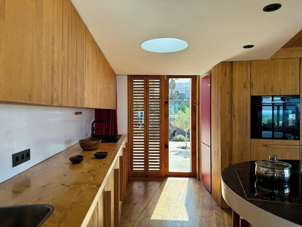 Una cocina moderna con armarios de madera, encimera negra y estufa integrada.