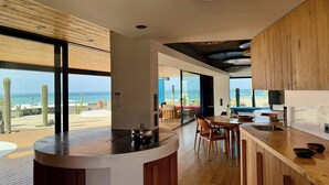Una cocina moderna con una isla grande, armarios de madera y vistas al océano.