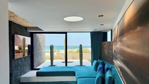 Una habitación moderna con un ventanal grande, un sofá azul y un cactus en el paisaje.