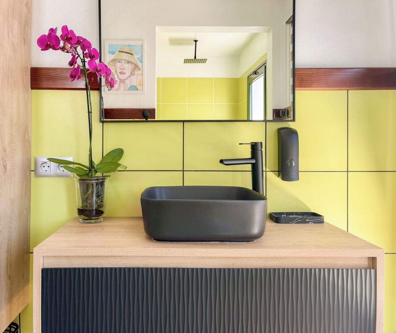 Un bagno moderno con un lavabo rettangolare, un rubinetto nero e uno specchio sopra.