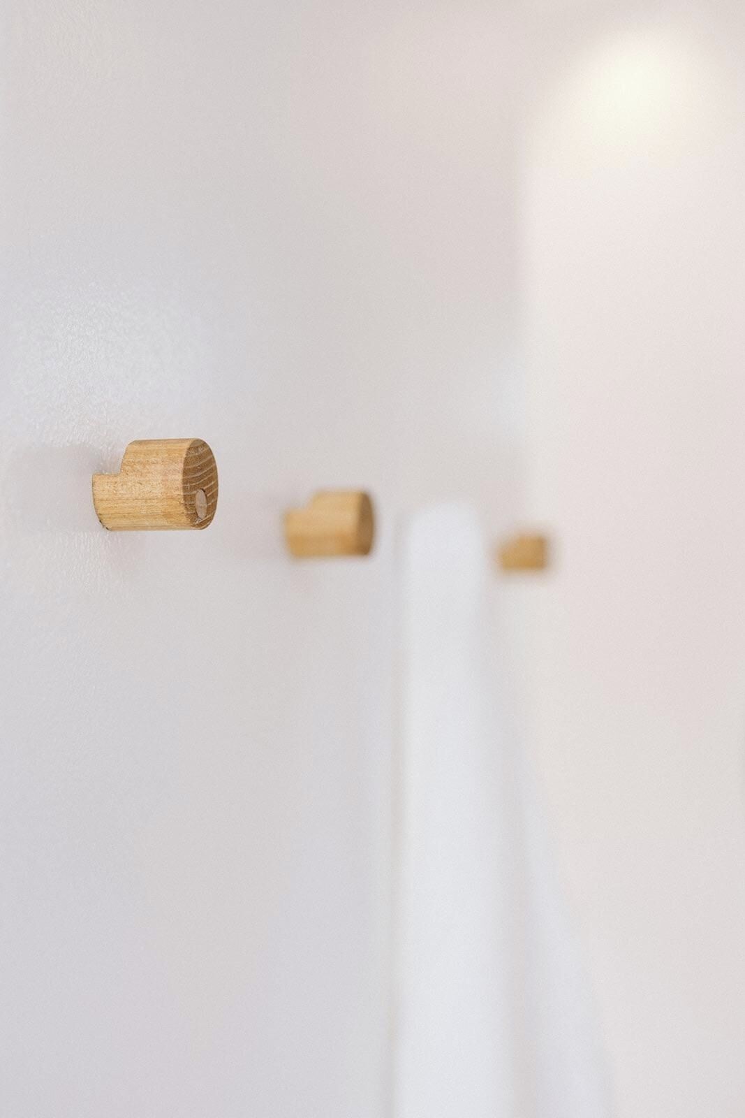 Drei hölzerne, zylinderförmige Objekte an einer weißen Wand.
