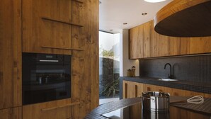 Une cuisine moderne avec des meubles en bois, un plan de travail noir et un four encastré.