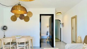 A modern living room with a dining area, a sofa, a coffee table, and a fan. - Canaryislandshost l Dalia (Puerto del Carmen)