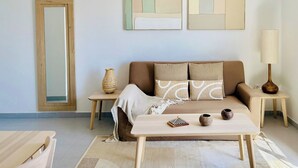 A modern living room with a sofa, two side tables, a lamp, and decorative items. - Canaryislandshost l Dalia (Puerto del Carmen)