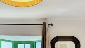 A hotel room with a bed, a window with a view, a mirror, and a curtain. - Canaryislandshost l Dalia (Puerto del Carmen)