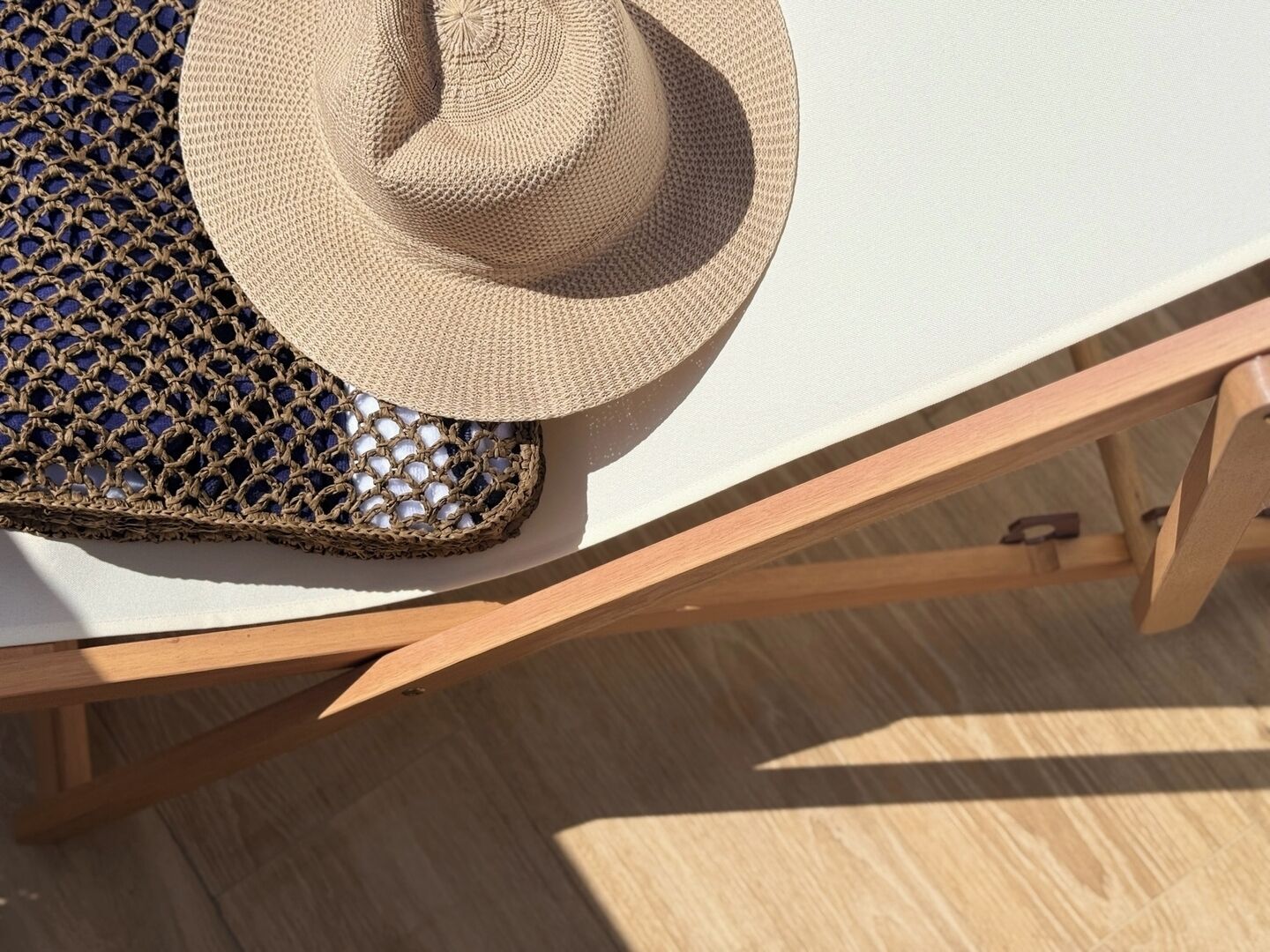 A woven basket and a straw hat on a wooden chair.