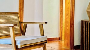 Una habitación con una silla de madera, una pared blanca y un suelo de madera.