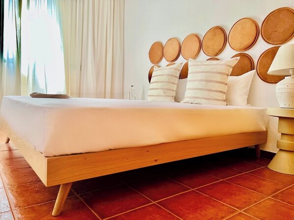 A bed with a wooden frame, white bedding, and multiple pillows.
