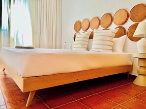 A bed with a wooden frame, white bedding, and multiple pillows.