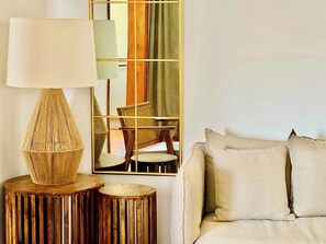 A room with a sofa, a lamp, a mirror, and a wooden stool.