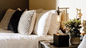 A neatly arranged bedroom with a bed, bedside tables, a lamp, and a potted plant. - The Bell Inn (Ladbroke)