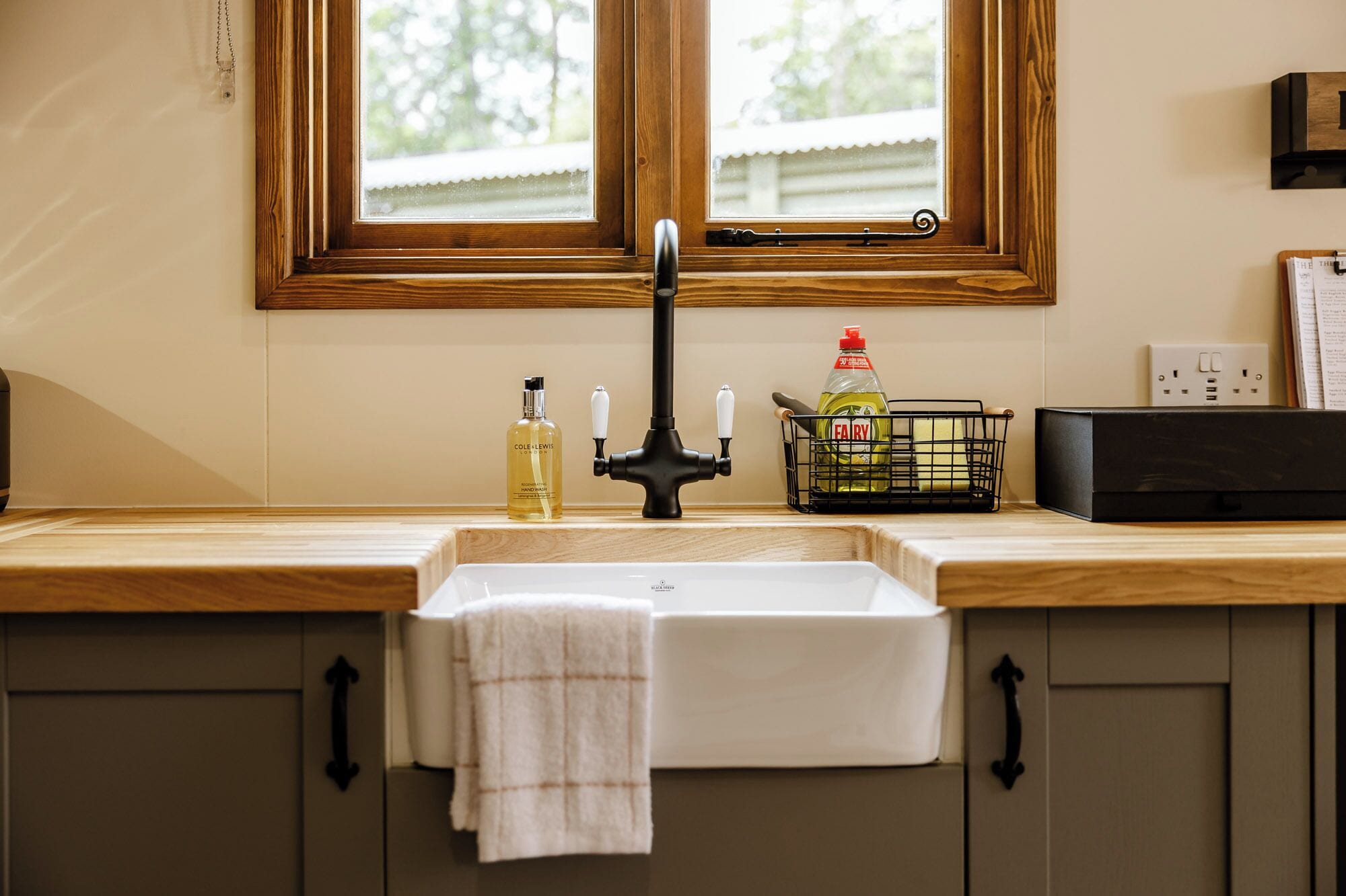 Una cocina con un lavamanos doble, encimeras de madera y una ventana sobre el lavamanos.